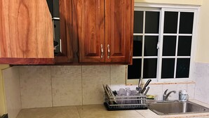 Una cocina con armarios de madera, estufa a gas, un lavamanos y una ventana.
