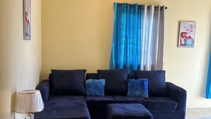 Una sala de estar con un sofá modular, una mesita auxiliar y una lámpara.