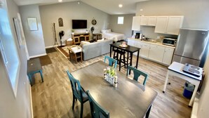 A modern apartment with a dining area, kitchen, living room, and a large window. - TC TWO OAKS Studio / Downtown / Clean & Spacious (Traverse City)