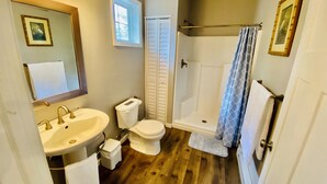 A bathroom with a sink, toilet, shower, and a window. - TC TWO OAKS Studio / Downtown / Clean & Spacious (Traverse City)