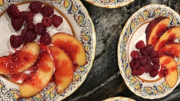 Cuatro ensaladas de frutas con frambuesas y melocotones sobre una encimera de mármol.
