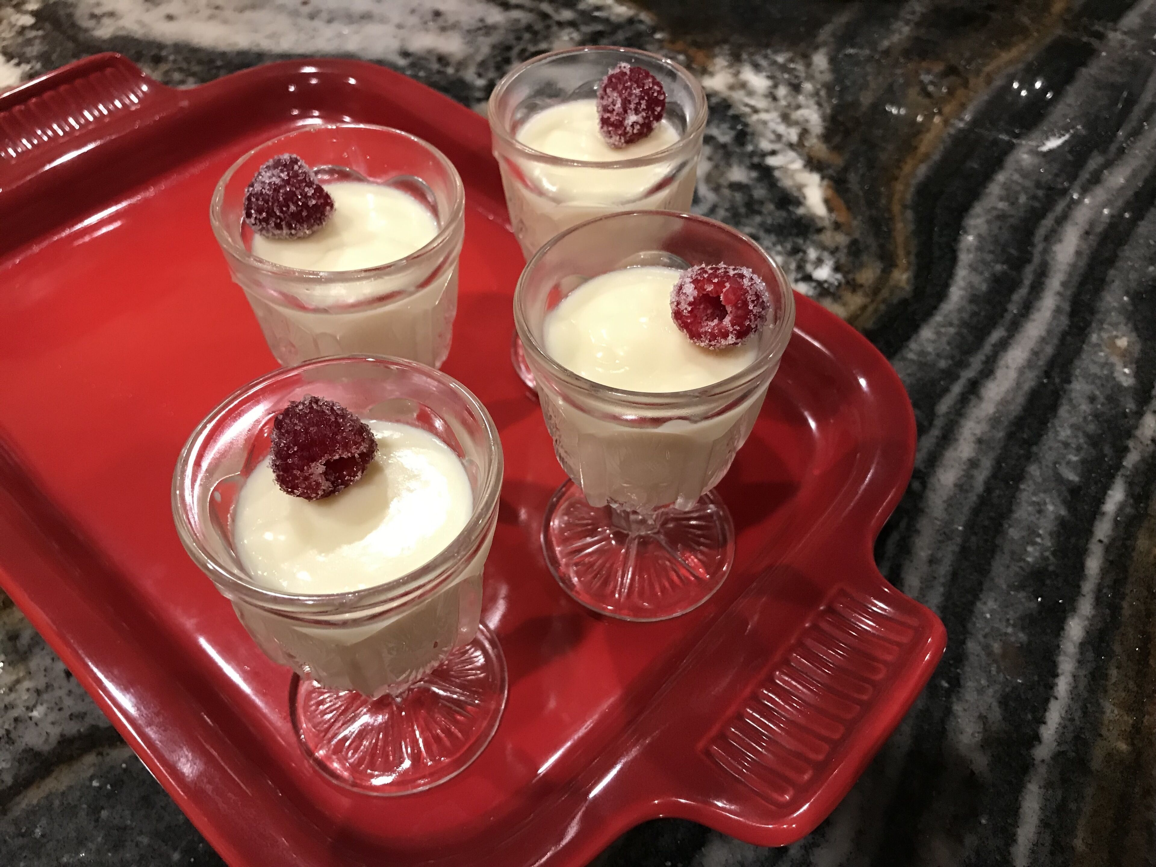 Four dessert glasses on a red tray.