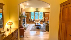 A spacious living room with a fireplace, comfortable seating, and a view through large windows.