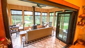 A cozy room with a large window, a ceiling fan, and a herringbone-patterned floor.