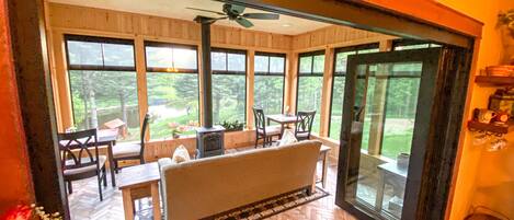 A cozy room with a large window, a ceiling fan, and a herringbone-patterned floor.