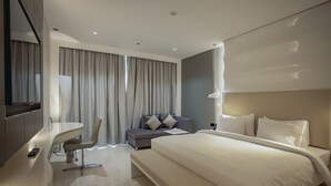 A modern hotel room with a large bed, a desk, a chair, and a sofa. - Alberni Jabal Hafeet Hotel (Al Ain)