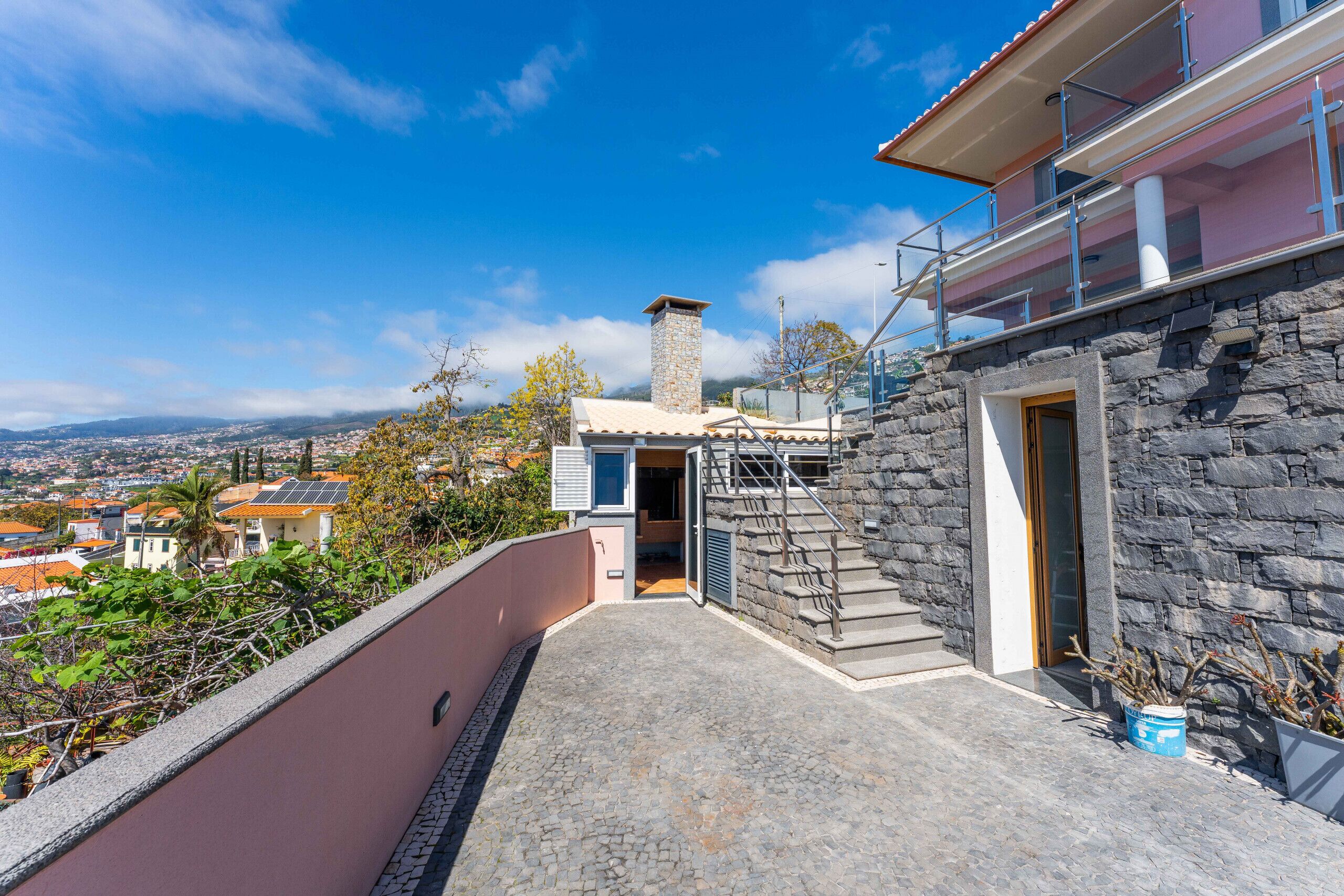 A stone building with a balcony, a staircase, and a view of a town.