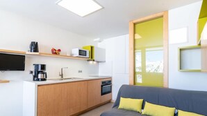 A compact living space with a kitchenette, a sofa, and a television. - Home Club (Lavachet) by Interhome (Tignes)