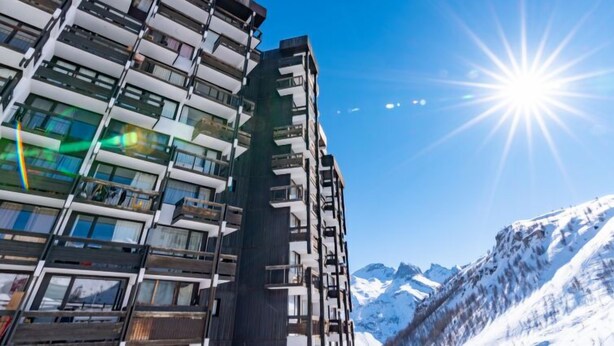 A multi-story hotel with balconies, a clear sky, and snow-covered mountains in the background. - Home Club (Lavachet) by Interhome (Tignes)