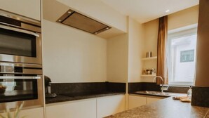 A modern kitchen with stainless steel appliances, a granite countertop, and a window with curtains. - Goethe close to the beach by Interhome (De Haan)