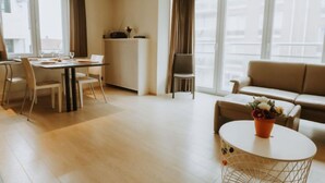 A modern living room with a dining area, a sofa, a coffee table, and large windows. - Goethe close to the beach by Interhome (De Haan)