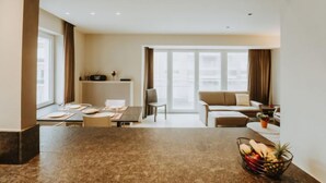 A modern living room with a sofa, a dining table with chairs, and a kitchen area with a counter and cabinets. - Goethe close to the beach by Interhome (De Haan)