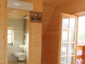 A wooden cabin bathroom with a toilet, sink, and a framed picture on the wall. - Holiday Home Ena (Plitvicka Jezera)