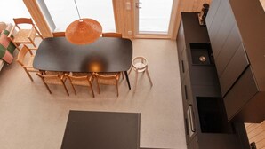 A modern interior with a dining area, wooden furniture, and a large window providing natural light.