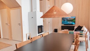 A modern kitchen with wooden cabinets, a large black dining table, and a hanging light fixture.