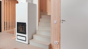A modern interior with a white fireplace, wooden paneling, and a staircase.