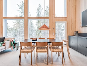 A modern interior with a dining table, chairs, and a hanging light fixture.
