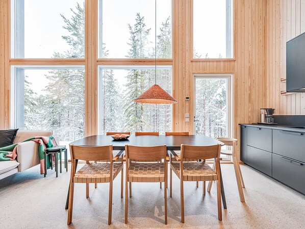 A modern interior with a dining table, chairs, and a hanging light fixture.