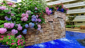 A hotel with a stone wall, a cascading water feature, and a pool with blue water.