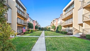 Un edificio residencial con varios balcones, un camino central y céspedes bien cuidados.