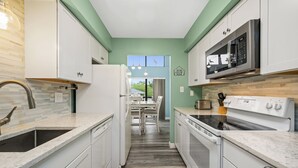Una cocina con gabinetes blancos, un refrigerador de acero inoxidable, un microondas y un horno.