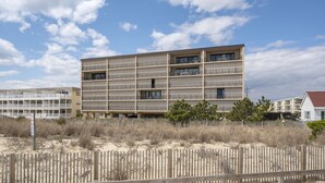Un hotel de varios pisos con balcones, situado cerca de una zona de playa arenosa.