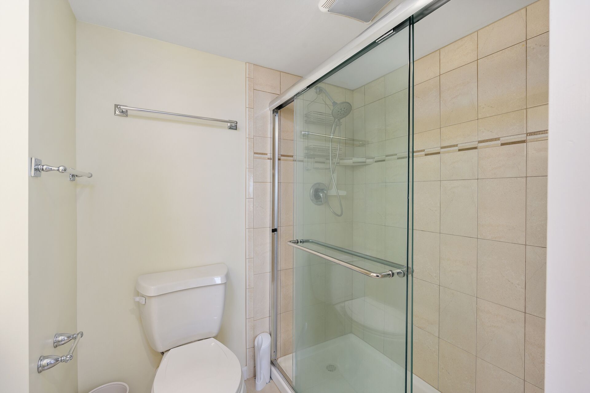 Un baño con ducha de vidrio, inodoro y puerta de vidrio para la ducha.