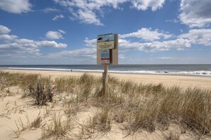 Een strandbord met een waarschuwing over roken en een strandkaart.