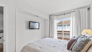 Ein Schlafzimmer mit Bett, einem Fenster mit Vorhängen, Blick ins Freie und einem Wandbild.