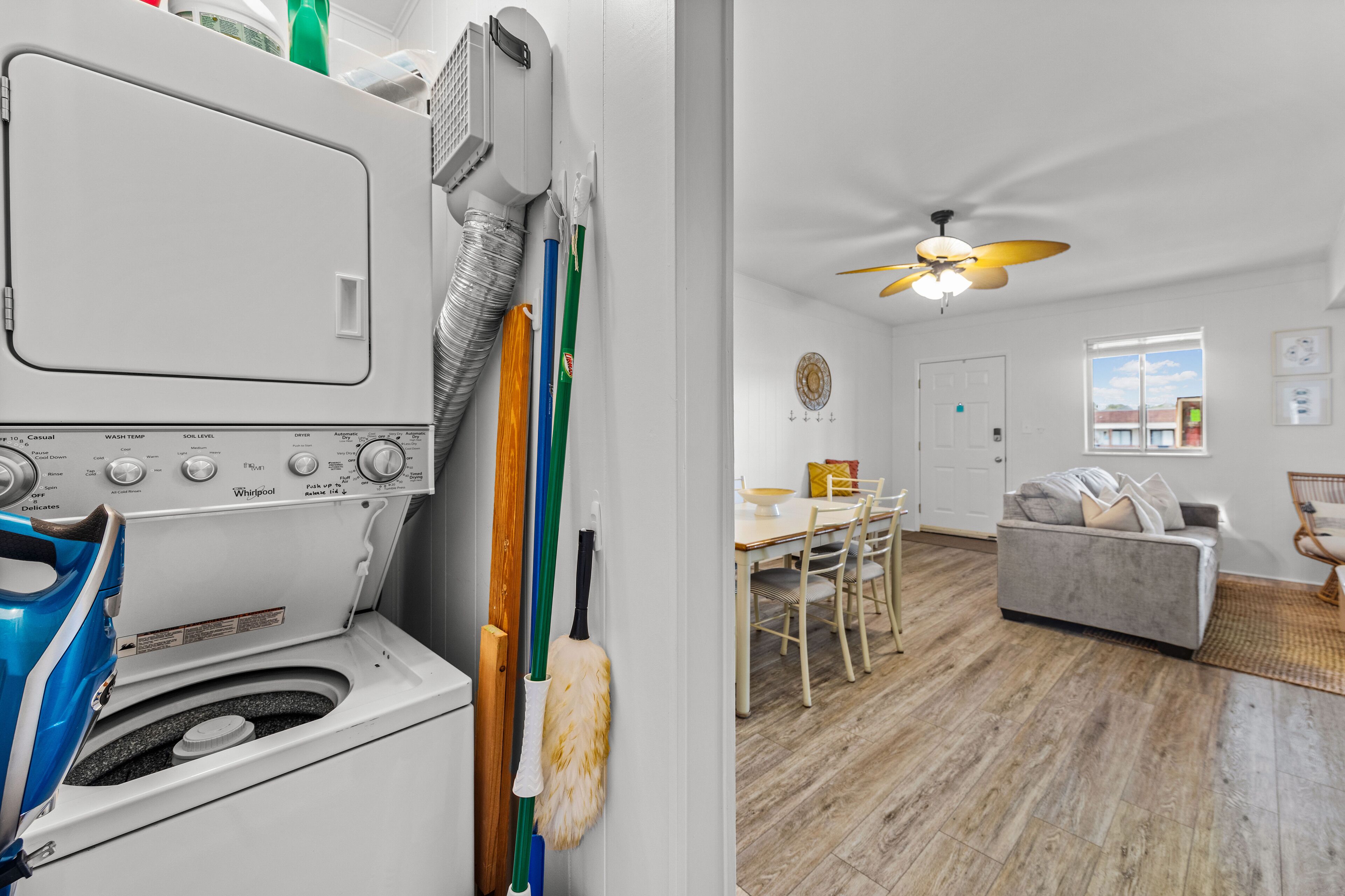 A laundry room with a washing machine, mops, and a ceiling fan.