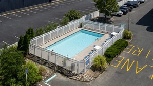A swimming pool surrounded by a white fence, with a parking lot in the background. - Maresol 502 by Seaside Vacations & Sales (Ocean City)