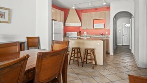 A kitchen with a central island, wooden chairs, and a dining table. - Maresol 502 by Seaside Vacations & Sales (Ocean City)