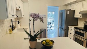 Eine moderne Küche mit weißen Schränken, einer zentralen Kochinsel und einem Topf mit einer Orchidee.