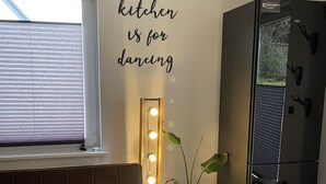 A kitchen with a bench, a refrigerator, and a wall with lights. - New, modern apartment with a great garden, centrally located - Bärs Kuschelhöhle (Gerolstein)