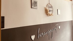 A wall with a 'WELCOME' sign, a framed picture, a 'Here is my home' sign, and a 'here is my home' text. - New, modern apartment with a great garden, centrally located - Bärs Kuschelhöhle (Gerolstein)