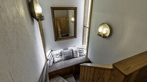 A wooden staircase with a bench at the top, a mirror, and wall-mounted lighting fixtures. - Your ultimate Sugar Mountain getaway - just steps from the slopes. (Sugar Mountain)