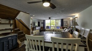 A dining area with a large wooden table and white chairs, a staircase with wooden railings, and a ceiling fan. - Your ultimate Sugar Mountain getaway - just steps from the slopes. (Sugar Mountain)