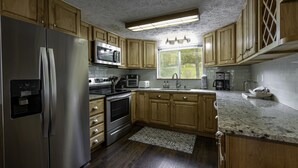 A kitchen with wooden cabinets, stainless steel appliances, a granite countertop, and a window with a view. - Your ultimate Sugar Mountain getaway - just steps from the slopes. (Sugar Mountain)