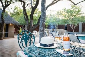 A table with a bottle of wine, a glass, and a hat. - Nkanyi Wildlife House & Cottage (Hoedspruit)