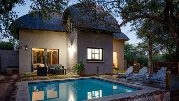 Ein Haus mit Swimmingpool, einer Terrasse mit Liegestühlen und einem überdachten Sitzbereich im Freien.
