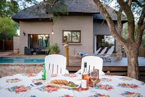 A poolside table with a floral tablecloth, a bottle of wine, and cookies.