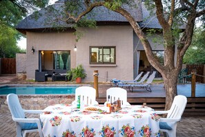 Une terrasse avec une piscine, une table à manger avec des chaises, et une plateforme avec des chaises longues.