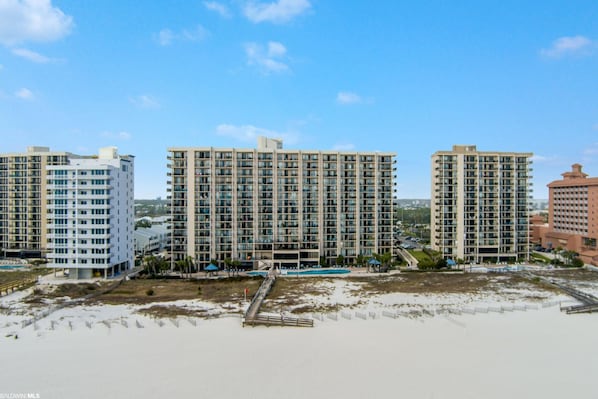 A beachfront hotel with multiple high-rise buildings, a sandy beach, and a pier.
