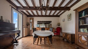 Un coin repas comprenant une table en bois, des chaises, un lustre, une horloge et une bibliothèque.