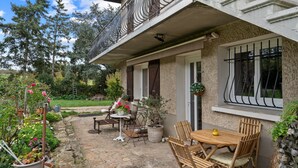 Une terrasse en pierre avec des meubles d’extérieur, un balcon doté de rampes en métal et des plantes en pot.