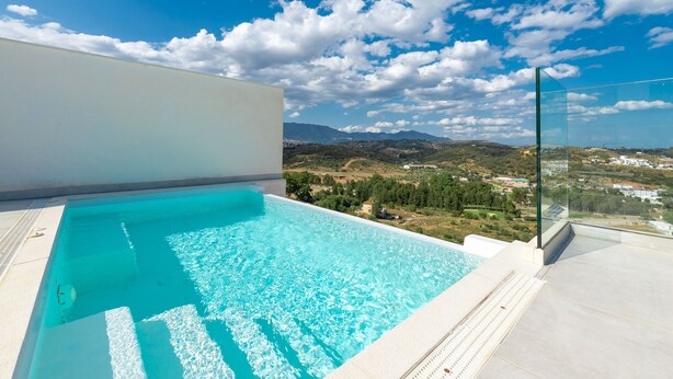 Piscina azul y cristalina con vistas a montañas lejanas y un cielo despejado.