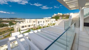 Un edificio moderno con balcón de cristal que da a la costa.