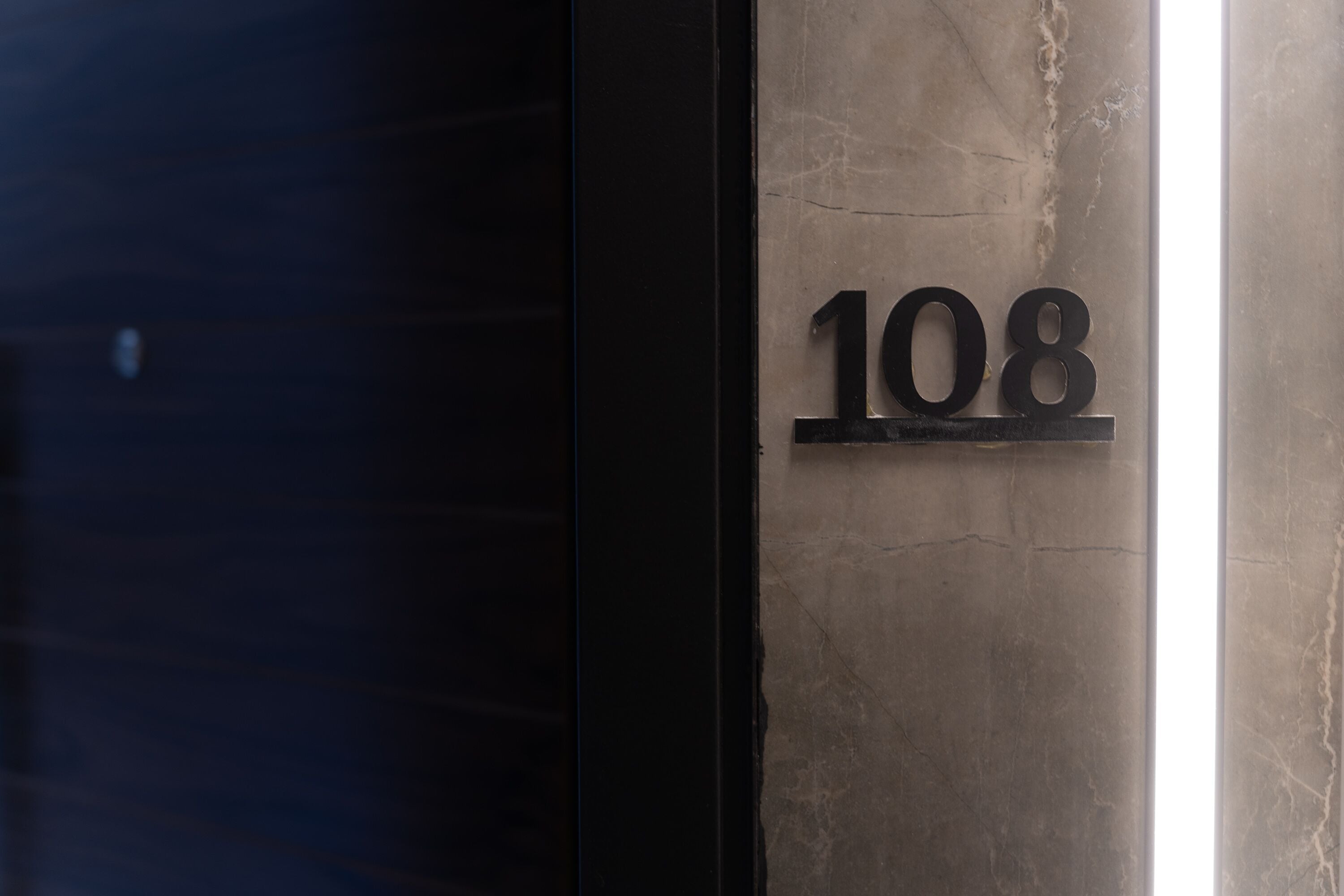 A building number '108' mounted on a marble wall.