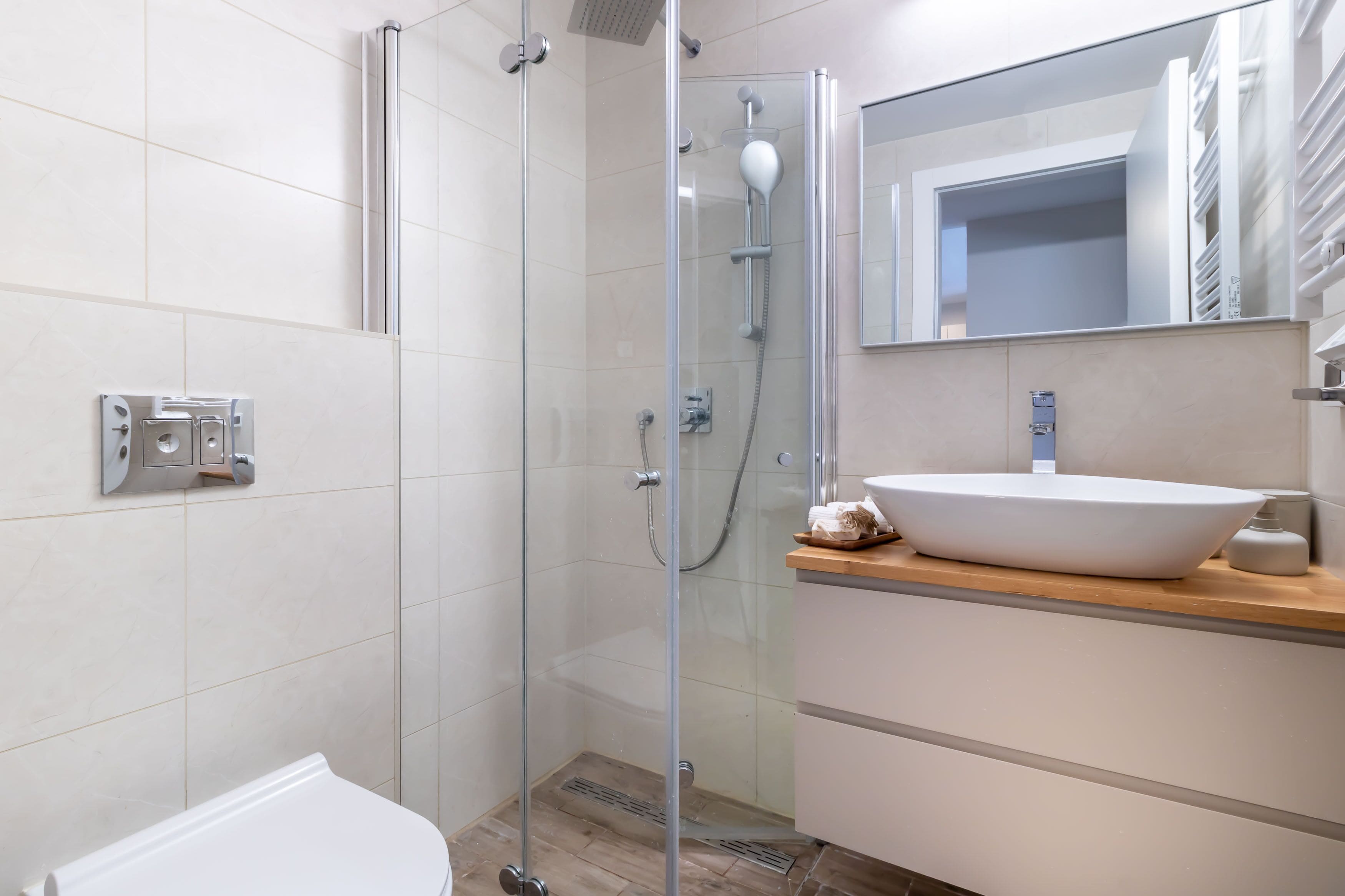 A modern bathroom with a glass-enclosed shower, a white sink, and a mirror above the sink.