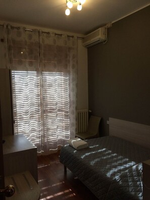 A bedroom with a bed, a radiator, and a window with curtains. - Twelve Hotel (Moncalieri)